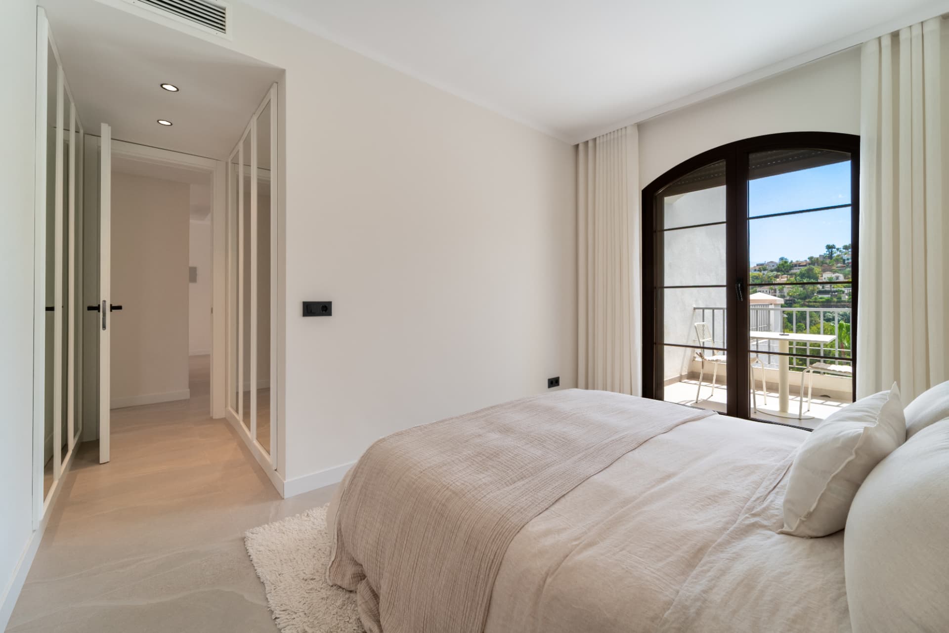 Bedroom with mirrored wardrobe and arched doors to the terrace