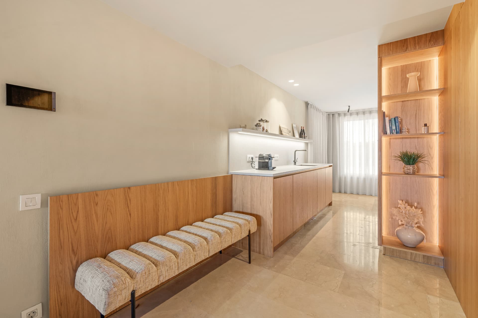 The entrance: a bench, a sink and a backlit oak display shelf
