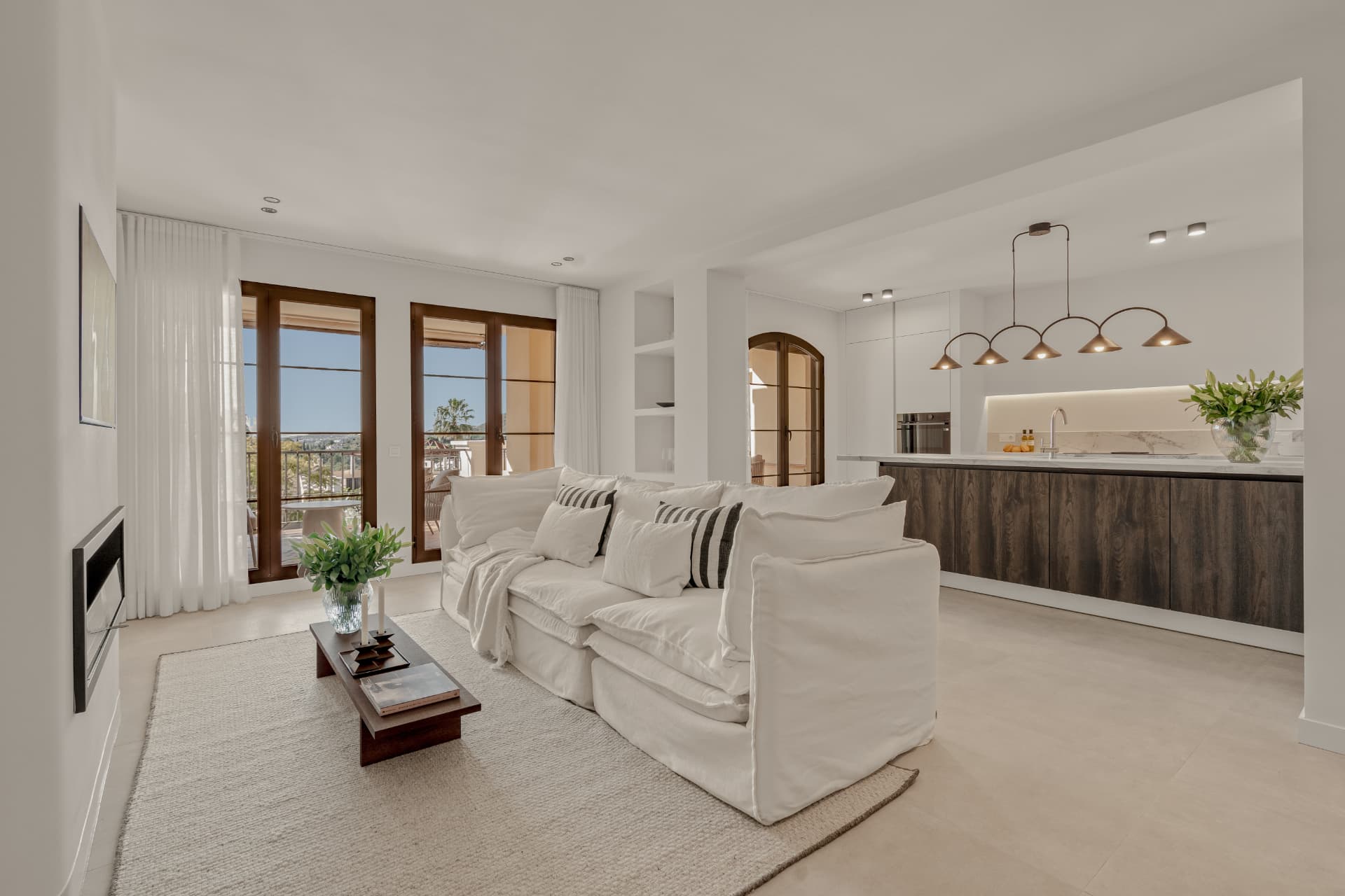 Open living room with white sofa and French doors to the terrace with views