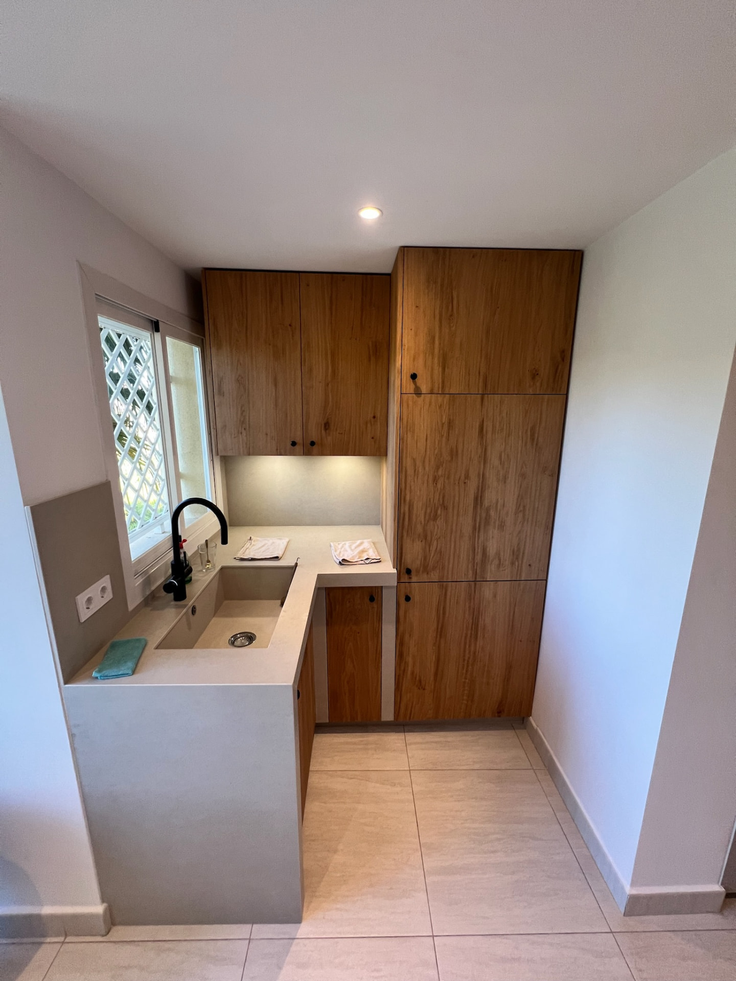 The kitchen after: the sink nook with a wood cabinet, undermounted sink and matte black tap