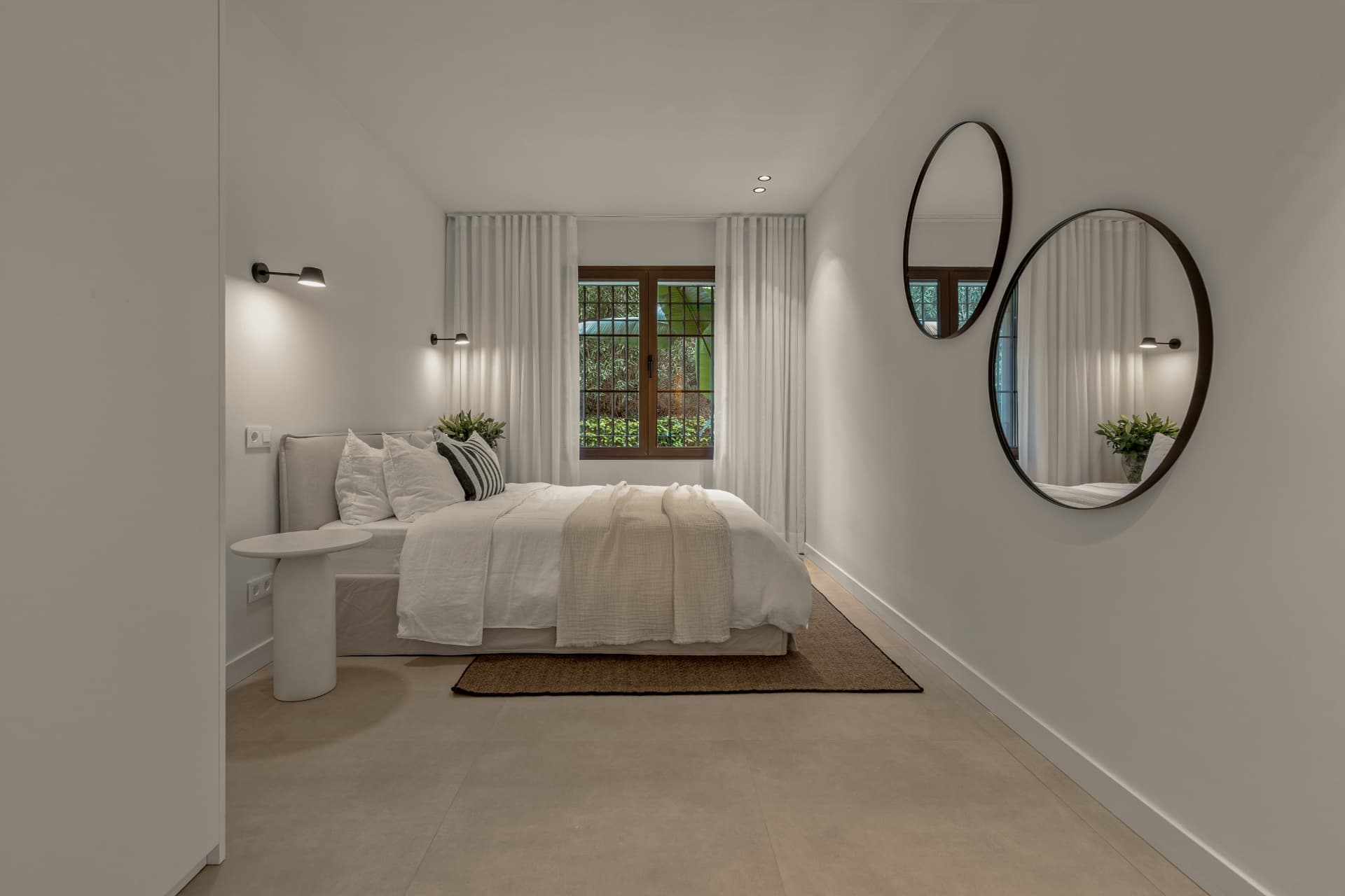 Bedroom with white curtains and round wall mirrors