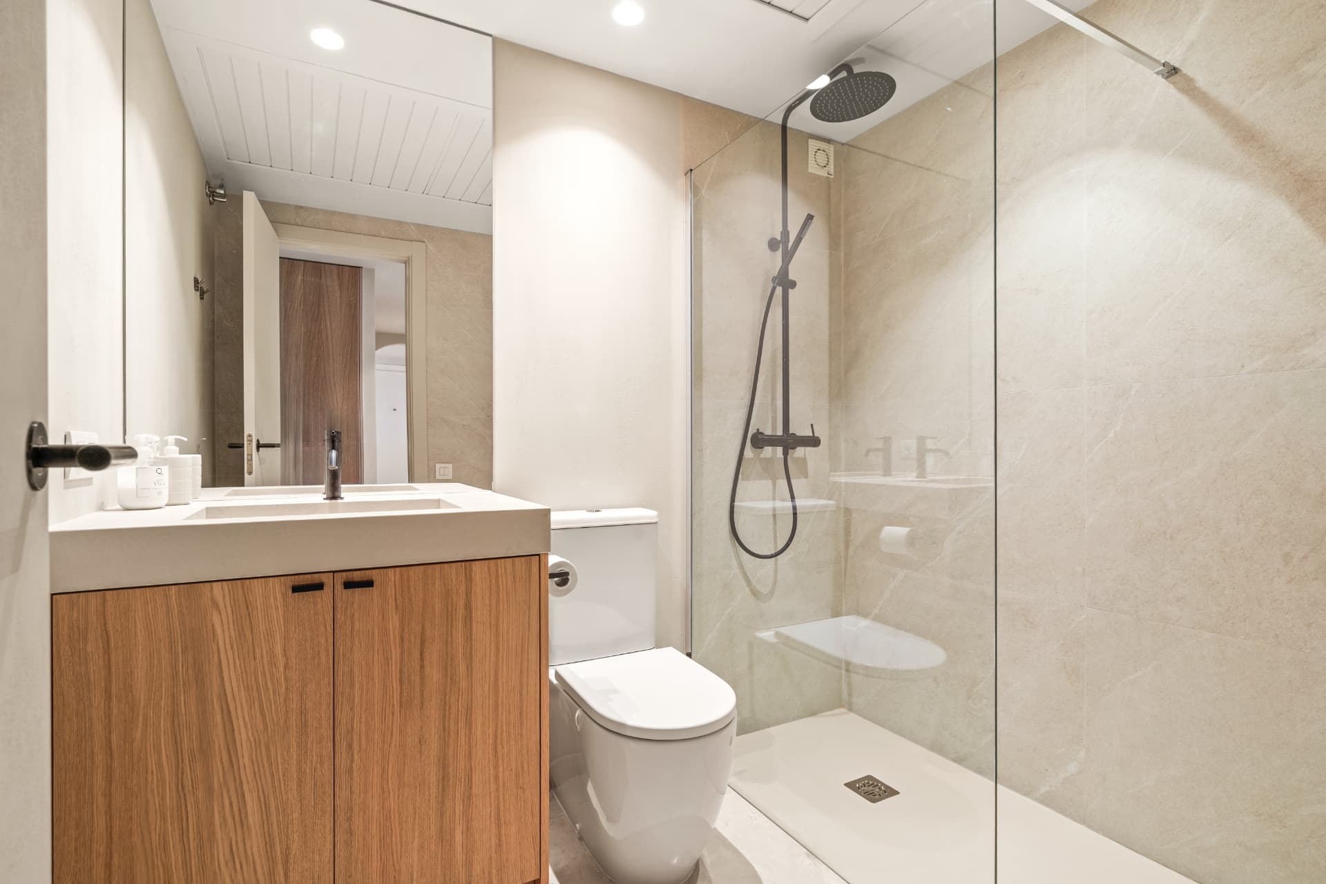 The second bathroom: an oak vanity with a trough basin and a walk-in shower with a matte black shower set