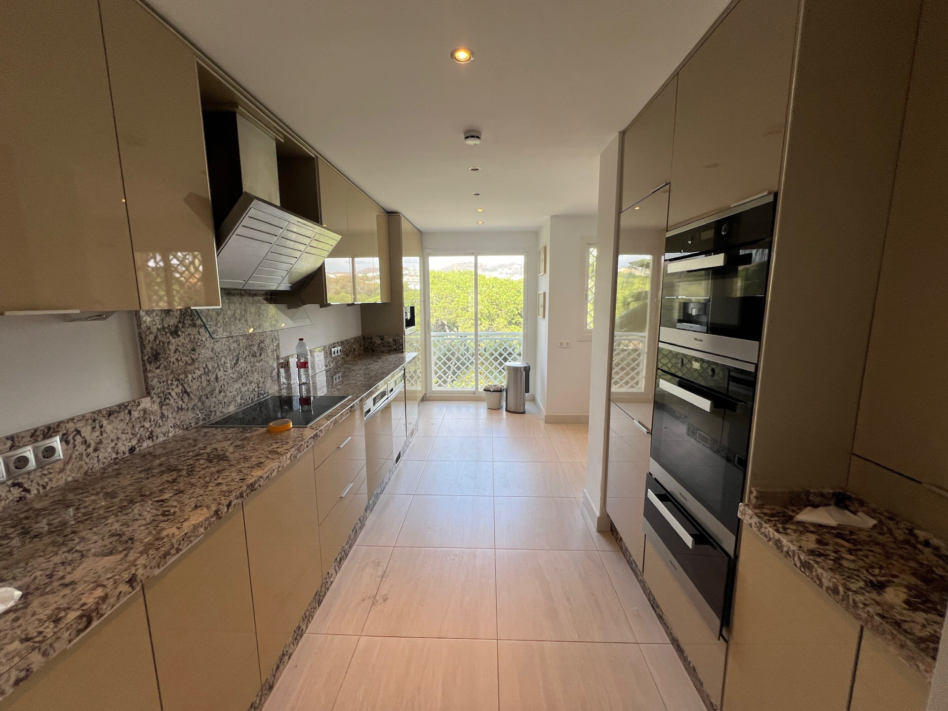 The kitchen before: glossy beige cabinets, speckled granite worktops and a tall unit with built-in ovens