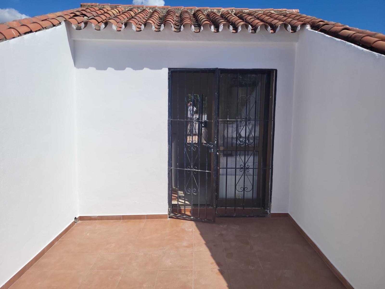 The terrace after: the new floor and walls along the entrance side, with the iron gate and glass door