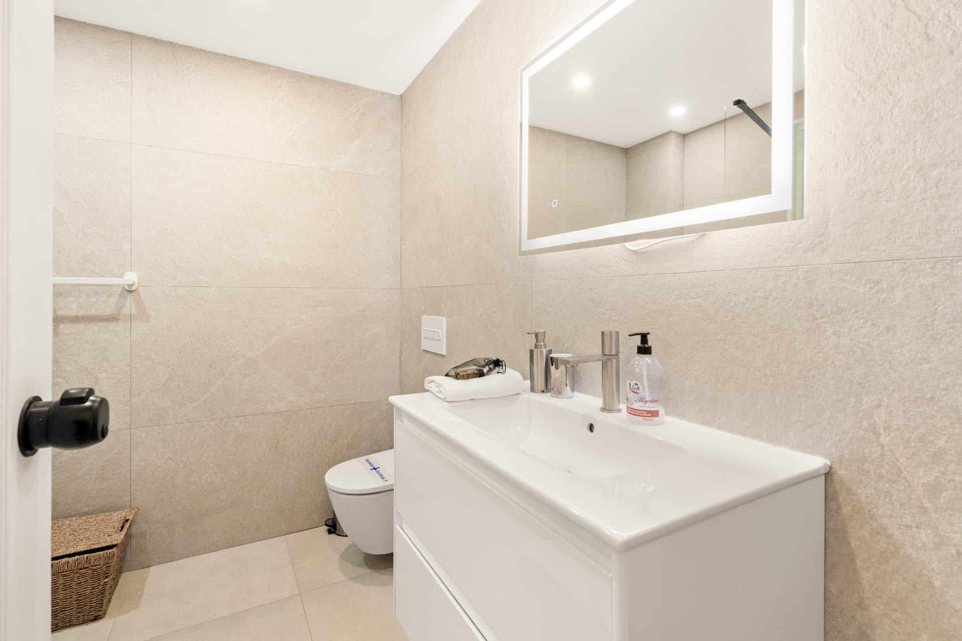 The bathroom after: a floating vanity with an integrated basin, a wall-hung toilet and a backlit mirror