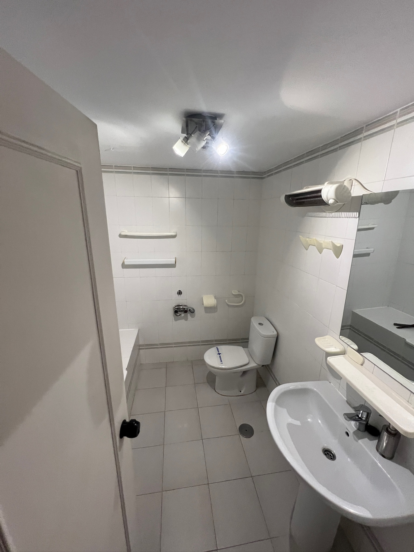 The bathroom before: small white wall tiles, a pedestal sink and a close-coupled toilet