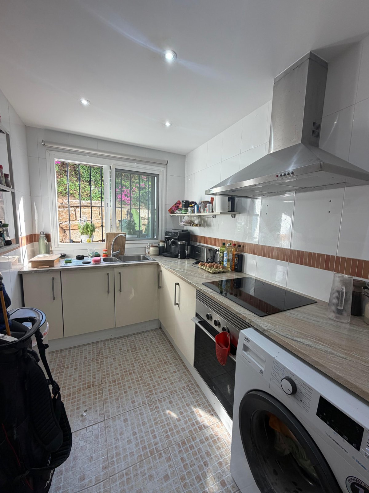 Kitchen in Alhaurín el Grande before the renovation: cream gloss cabinets, white wall tiles and a steel extractor hood
