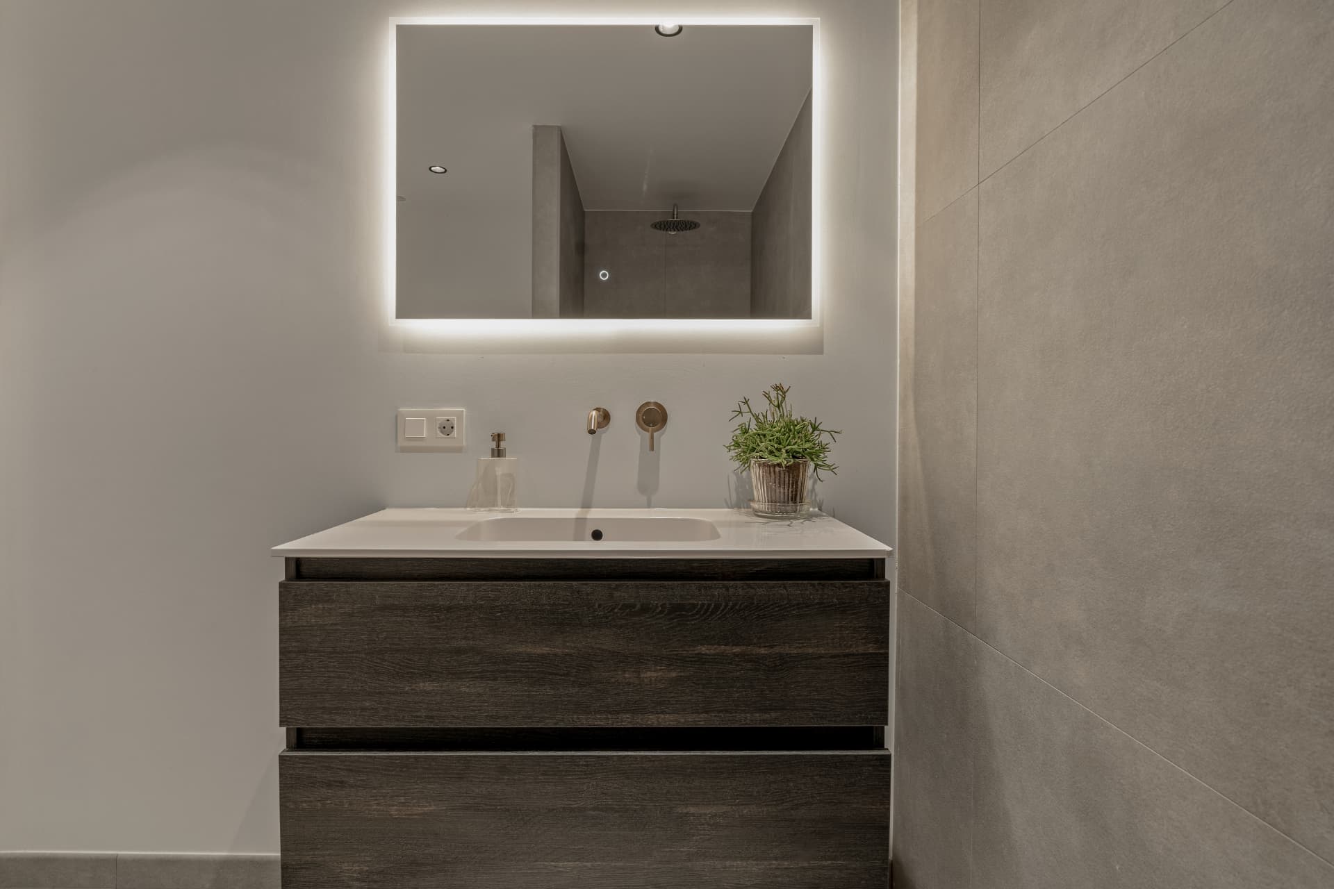 Bathroom with dark oak vanity and backlit mirror