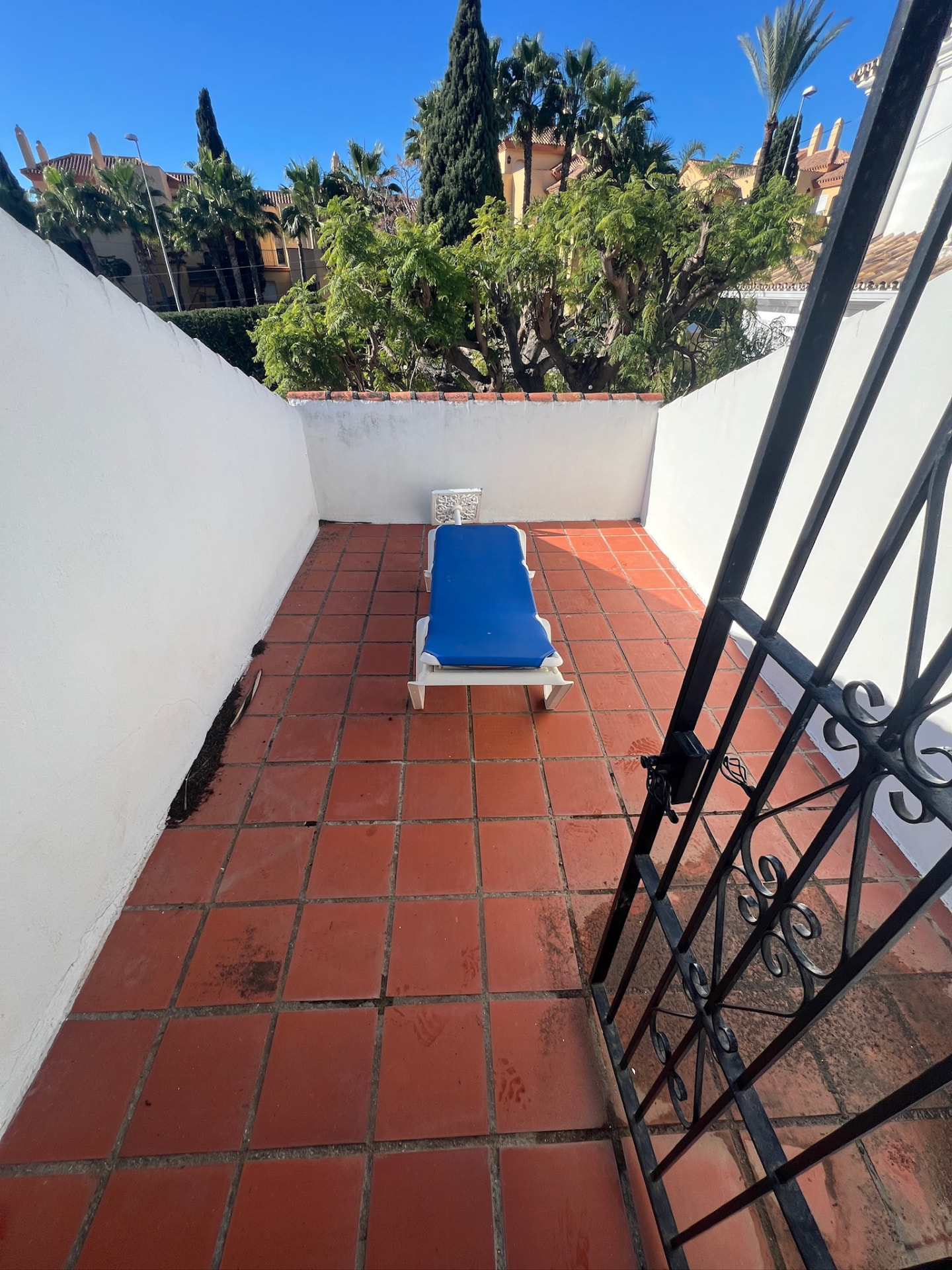 The terrace before: weathered red floor tiles, an old sun lounger and a stained parapet wall