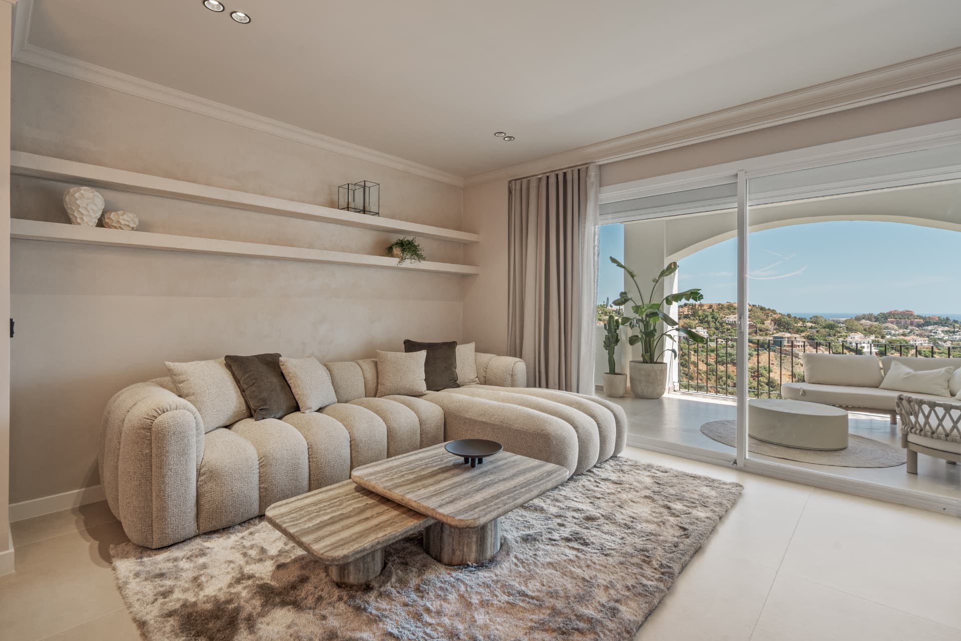 Living room with curved sofa and sliding doors to the terrace with sea view