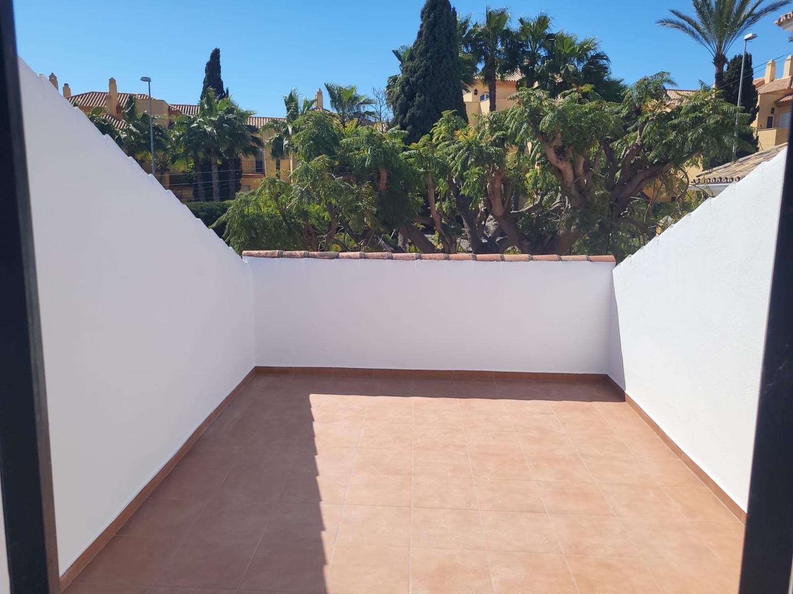 The same terrace after: clean new tiles, freshly painted white walls and the same view over the rooftops