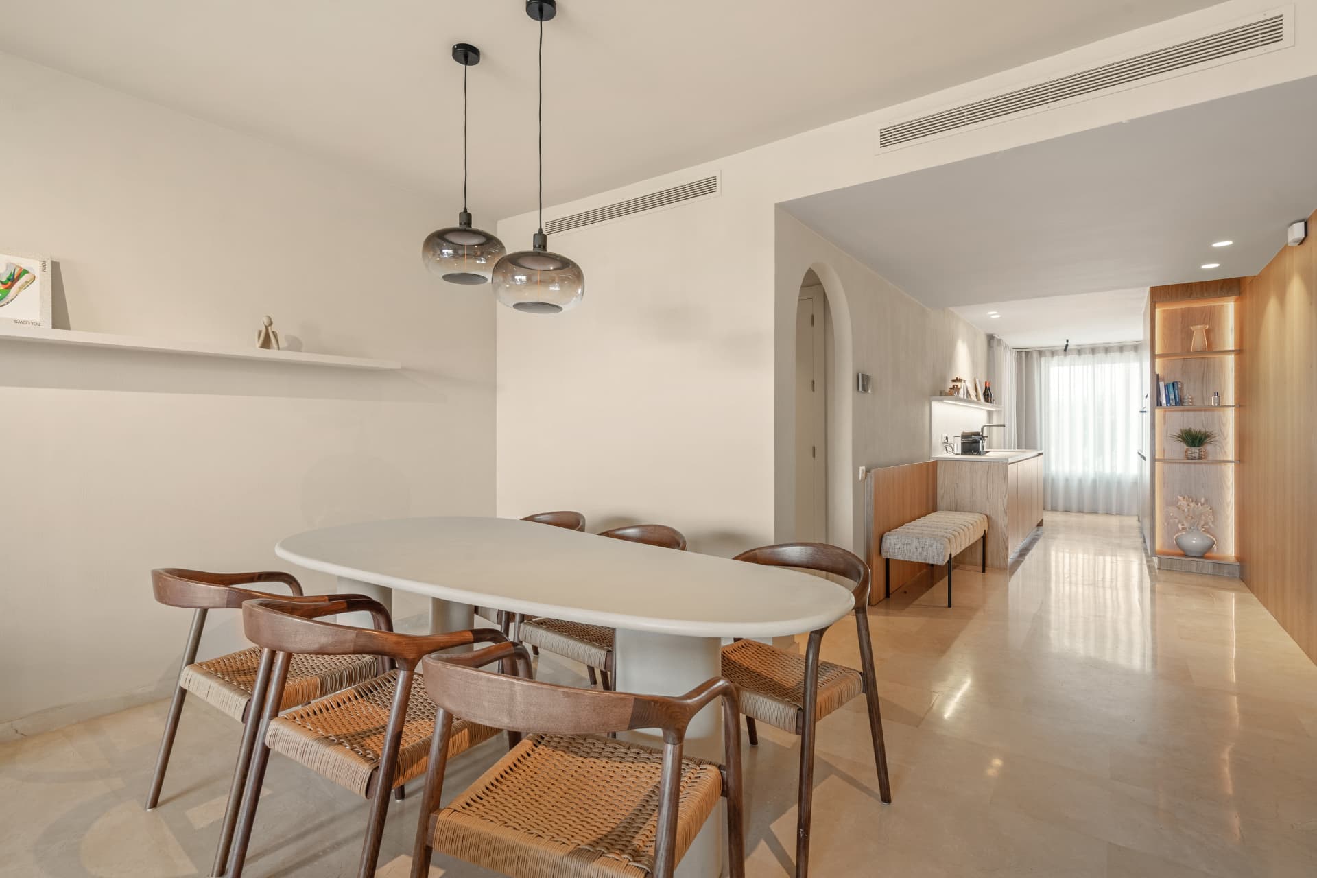 The dining area in front, with the hallway beyond and lit oak shelving on the right